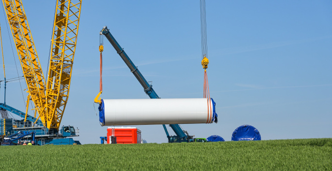 Repowering. Ein Teil von einem Windrad wird an einem Kran transportiert.