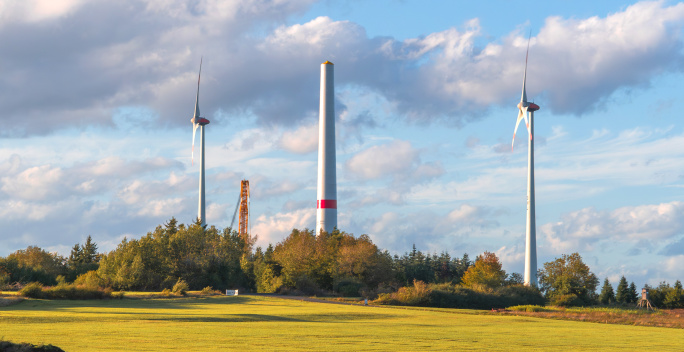 Auf dem Bild sieht man zwei Windräder und ein Windrad im Bau, bei dem die Gondel und Rotorblätter noch nicht angebaut sind.