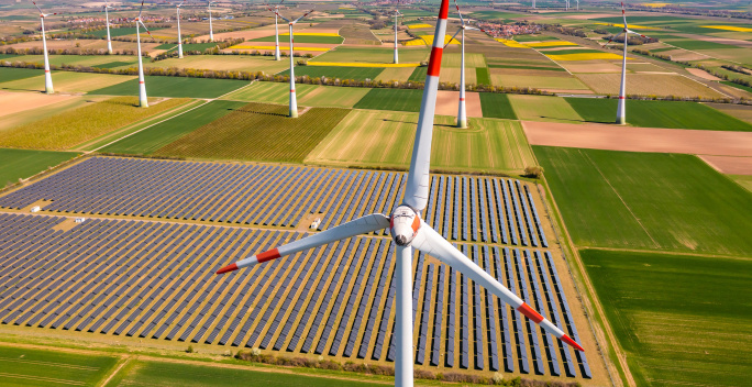 Windrad aus der Luft fotografiert, weitere Windenergieanlagen und eine Solarpark im Hintergrund