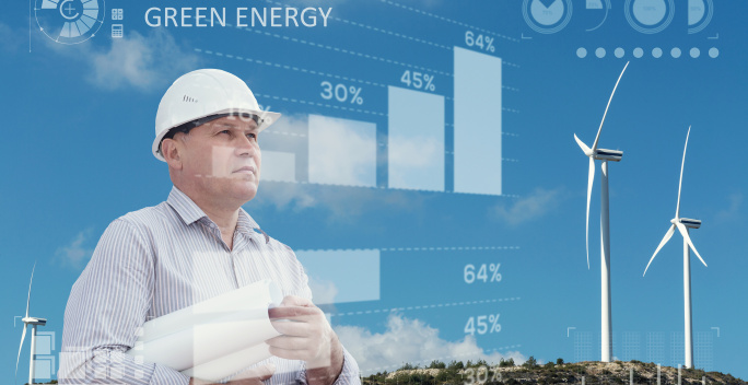 Auf diesem Bild schaut sich ein Mann verschiedene graphische Darstellungen an. Im Hintergrund sind Windkraftanlagen zu erkennen.