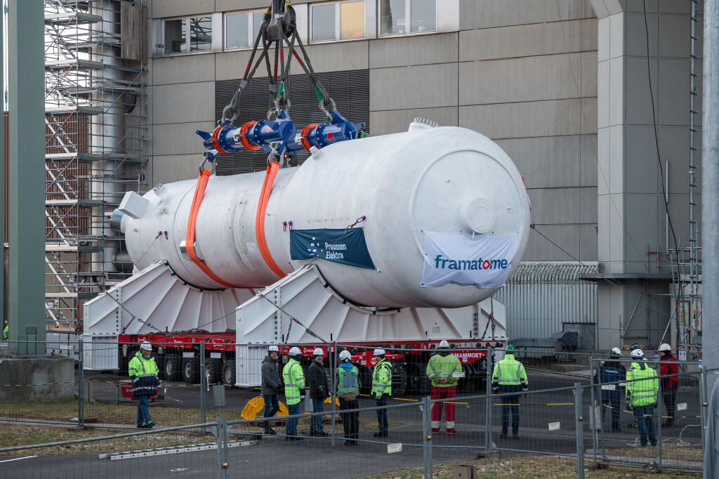 Ein Dampferzeuger wird mithilfe eines Schwerlastkrans aus dem Reaktorgebäude gehoben und auf zwei Träger für den Weitertransport montiert.