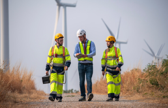 Drei Ingenieure vor Windkraftanlagen